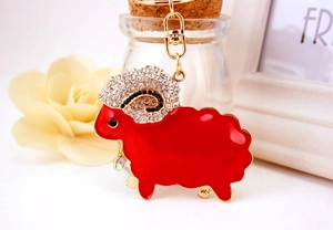 Detailed close-up of a red enamel sheep keychain with rhinestones and golden hardware