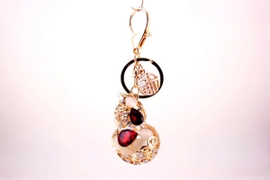 Macro detail of golden gourd keychain with red teardrop gemstones and 福 character tag