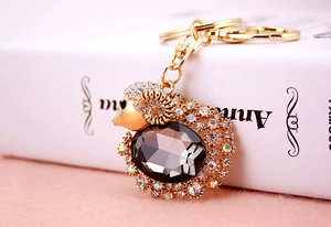 Close-up of golden goat keychain with sparkling crystals and large grey gemstone