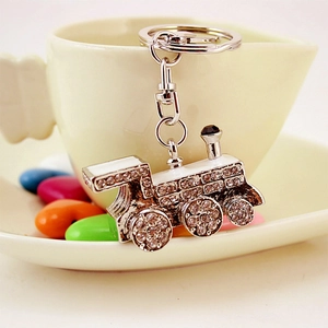 Sparkling silver train locomotive keychain with rhinestones on a coffee cup background