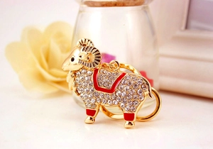 Détail macro du porte-clés chèvre avec strass blancs et émail rouge sur base dorée