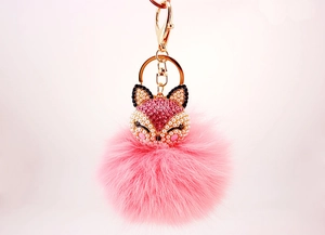 Macro detail of fox head keychain with pink faux fur pompom and sparkling rhinestones