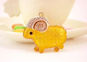Detail of a golden goat keychain with yellow enamel texture and sparkling rhinestones
