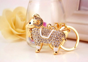 Détail de porte-clés chèvre dorée avec cristaux strass et finitions en émail blanc