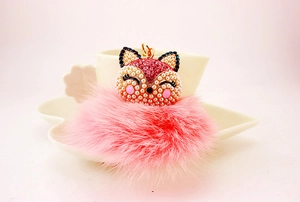 Detailed close-up of pink fox head keychain with fluffy fur ball and gold metal clasp