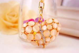 Macro-opname van een gouden hartvormige sleutelhanger met opaal en strass details