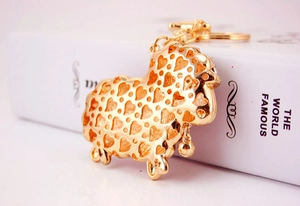 Detail shot of golden sheep keychain with heart hollow pattern and mini bell