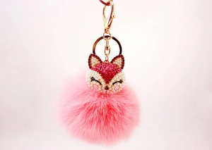 Close-up of pink fluffy fox fur ball keychain with rhinestone fox head and gold clip