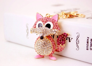 Close-up of pink and white crystal fox keychain with golden metal base and rhinestones