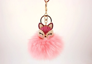 Close-up of pink fox head keychain with rhinestones, pearls and a fluffy fur pompom