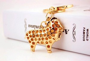 Détail d'un porte-clés mouton doré avec motifs floraux creux et ornements en cristal