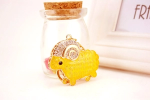 Detailed close-up of a cute goat keychain with yellow enamel and sparkling rhinestones