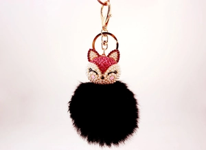 Detailed macro view of black faux fur ball keychain with rhinestone fox head and gold clasp