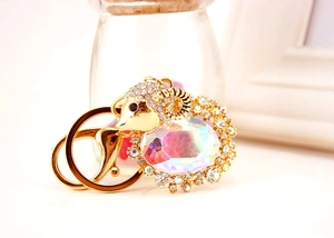 Detail of cute goat keychain with golden base, white crystals and large iridescent gemstone