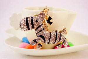 Macro view of gold zebra keychain with sparkling crystals and black enamel stripes