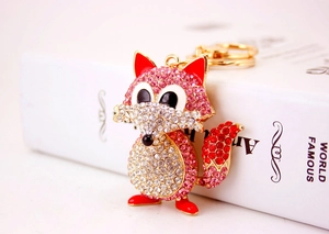 Macro shot of cute fox keychain with pink and white crystals and red enamel details