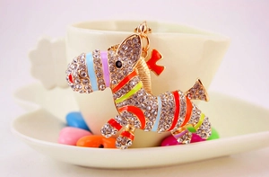 Detail of creative zebra keychain with colorful rhinestones leaning on a coffee cup