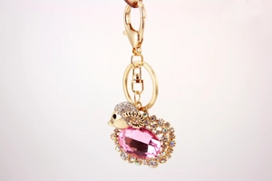 Detail of cute goat keychain featuring a large pink crystal with sparkling gold accents