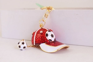 Detail of red sports cap keychain with football charm and gold metal finish