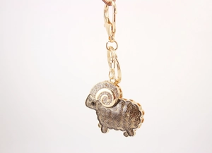 Close-up of golden goat keychain with white rhinestones and brown enamel details