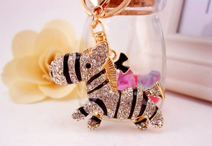 Close-up of golden zebra keychain featuring sparkling rhinestones and black enamel stripes