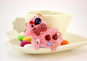 Cute pink sheep keychain with colorful rhinestones leaning on a white ceramic cup