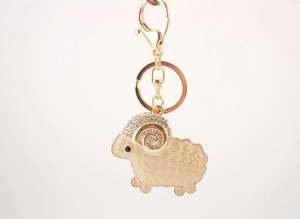 Close-up of golden goat keychain with sparkling rhinestones and white enamel finish