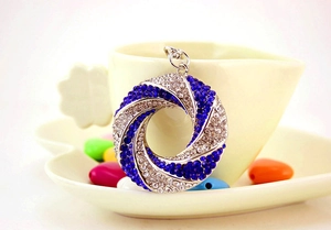 Macro detail of a sparkling silver keychain with blue and white crystals on a white cup