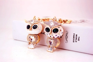 Détail des porte-clés hibou dorés avec cristaux en cœur et accents de strass étincelants
