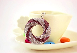 Detail of a purple and white rhinestone swirl metal keychain beside a coffee cup