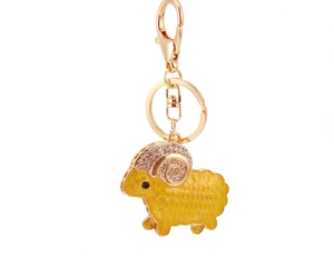Macro detail of golden goat keychain showing yellow enamel texture and white rhinestones