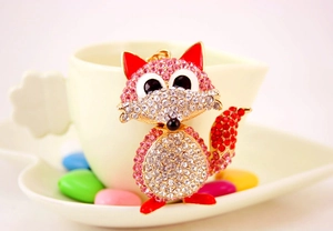 Detailed view of fox keychain with pink rhinestones and red enamel ears on a ceramic cup