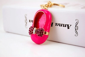 Macro shot of pink embroidered shoe keychain with rhinestone bow and gold chain detail