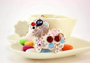 Detail of cute sheep keychain with colorful rhinestones on a heart-shaped porcelain cup