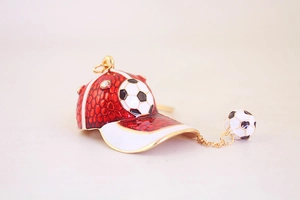 Macro detail of red and white enamel football cap keychain with rhinestones and gold charm