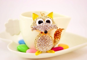 Detail of crystal fox keychain with champagne rhinestones on a white ceramic cup