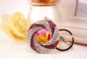 Detail of creative round keychain with purple and white rhinestones in spiral pattern