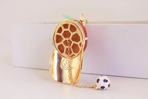 Detail of red hollowed hat keychain with gold finish and mini soccer ball charm