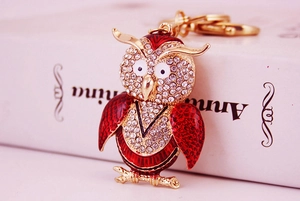 Détail du porte-clés hibou avec ailes en émail rouge et cristaux étincelants sur métal doré