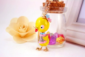 Close-up of yellow duck keychain with rhinestones and enamel flower details on a desk