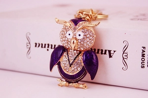 Détail d'un porte-clés hibou avec émail violet et strass blancs sur métal doré