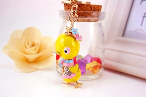 Detail of a yellow duck keychain with rhinestones and pink floral vest on metal hook