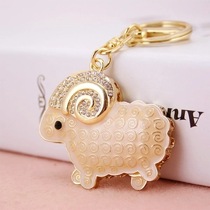 Charming golden ram keychain with white enamel, rhinestones and elegant spiral details