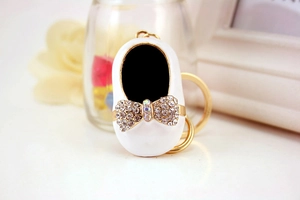 Close-up of white ballet shoe keychain with sparkling rhinestones and golden ring detail