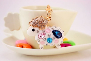 Détail d'un porte-clés mouton en émail blanc avec strass colorés sur une tasse en céramique