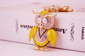 Gros plan du porte-clés hibou avec strass étincelants et émail jaune sur base en métal doré