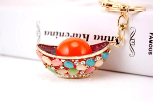 Detailed close-up of a Chinese gold ingot keychain with crystals and orange faux pearl