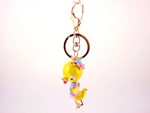 Detailed macro view of yellow enamel duck keychain with rhinestones and rose gold lobster clasp
