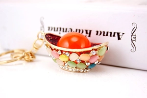 Macro view of gold ingot keychain with colorful crystals and a large orange pearl bead