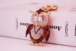 Gros plan détaillé du porte-clés hibou doré avec strass blancs et détails en émail brun
